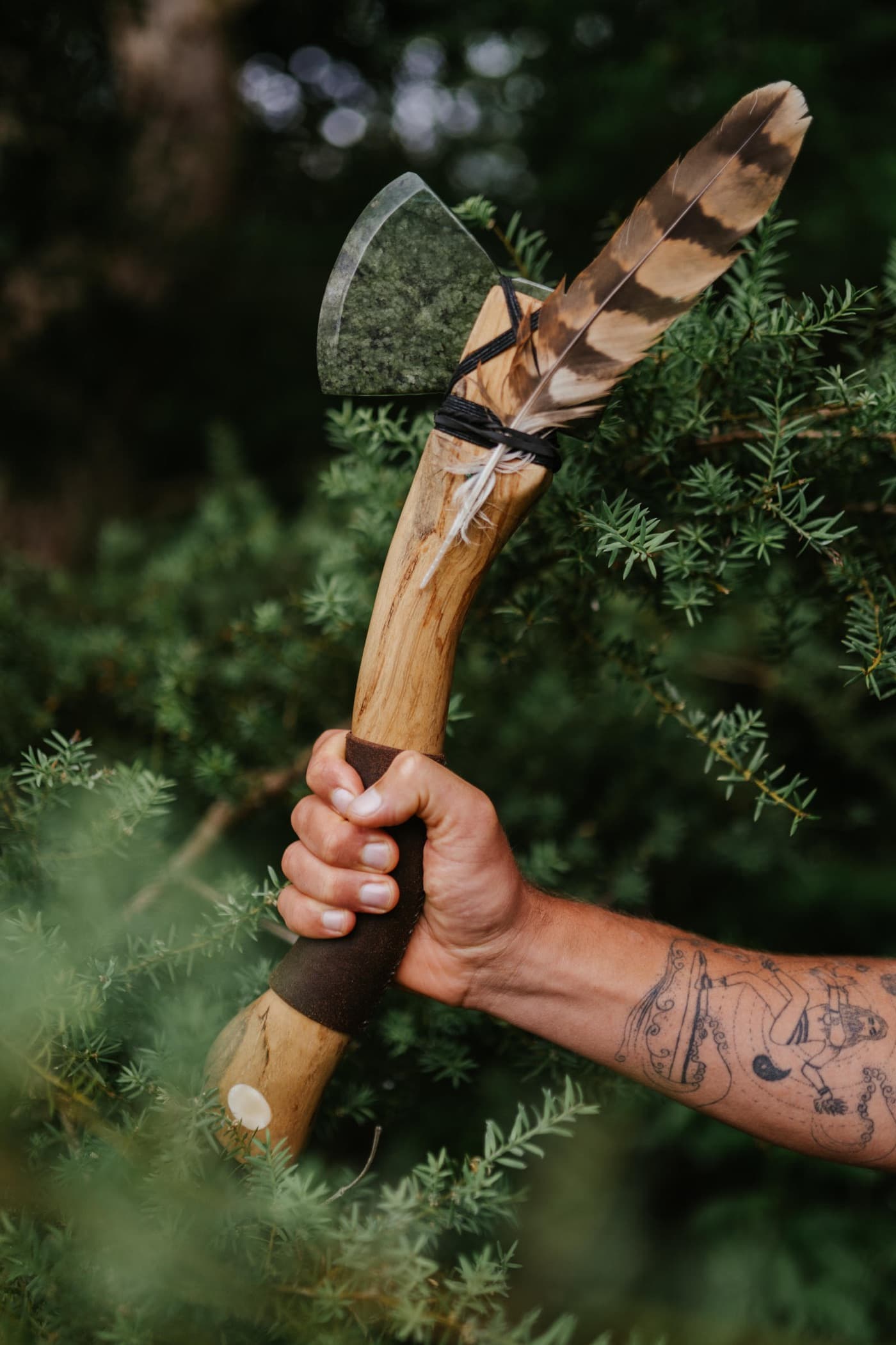 A hand raising a carved axe with a feather