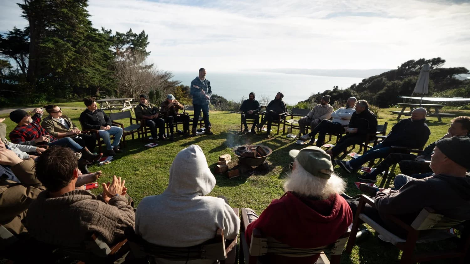 A circle of men gathered above the coast at a BROS leadership training