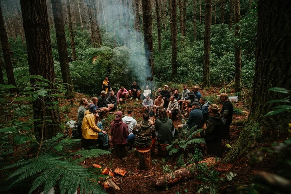 A circle of men in the forest around a fire